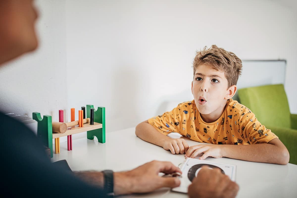 chłopiec ćwiczący z logopedą